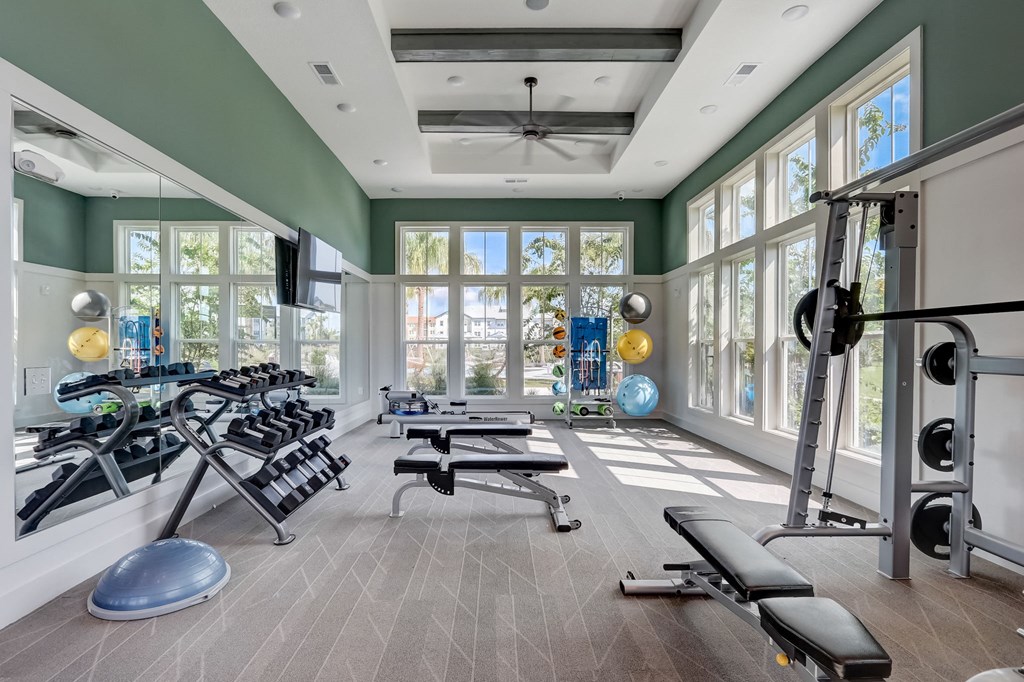 the home gym has plenty of exercise equipment and windows