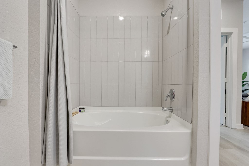 a white bathroom with a tub and a shower curtain