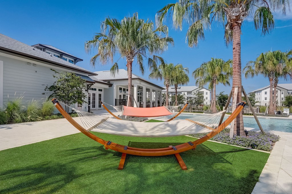 a hammock in the backyard of a house with a pool