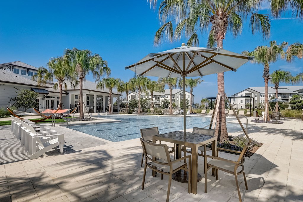 a swimming pool with a table and chairs under an umbrella