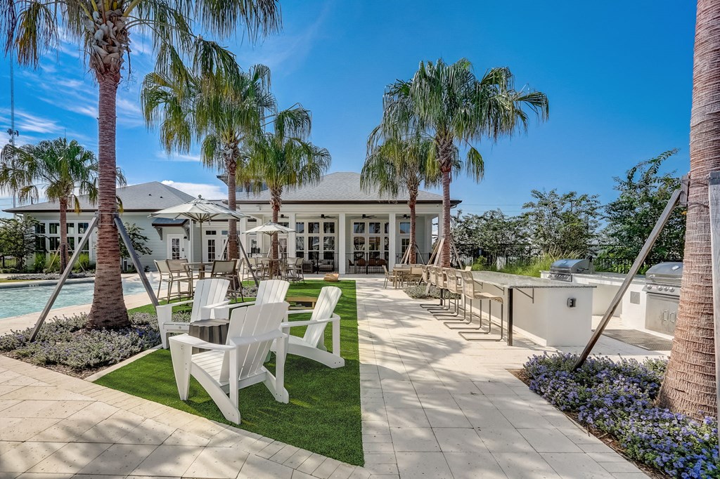 a patio with chairs and palm trees in front of a house