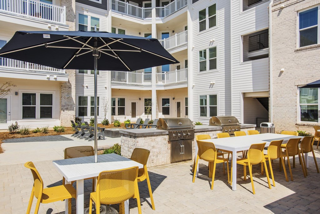 our patio has tables and chairs with umbrellas and a grill