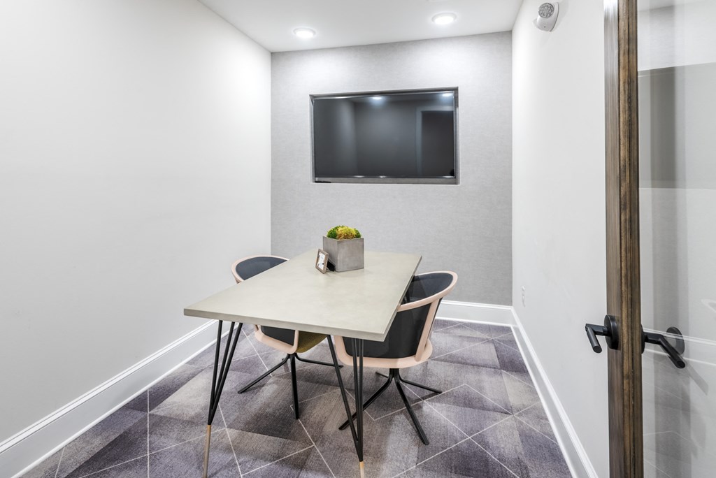 a conference room with a table and chairs and a television on the wall