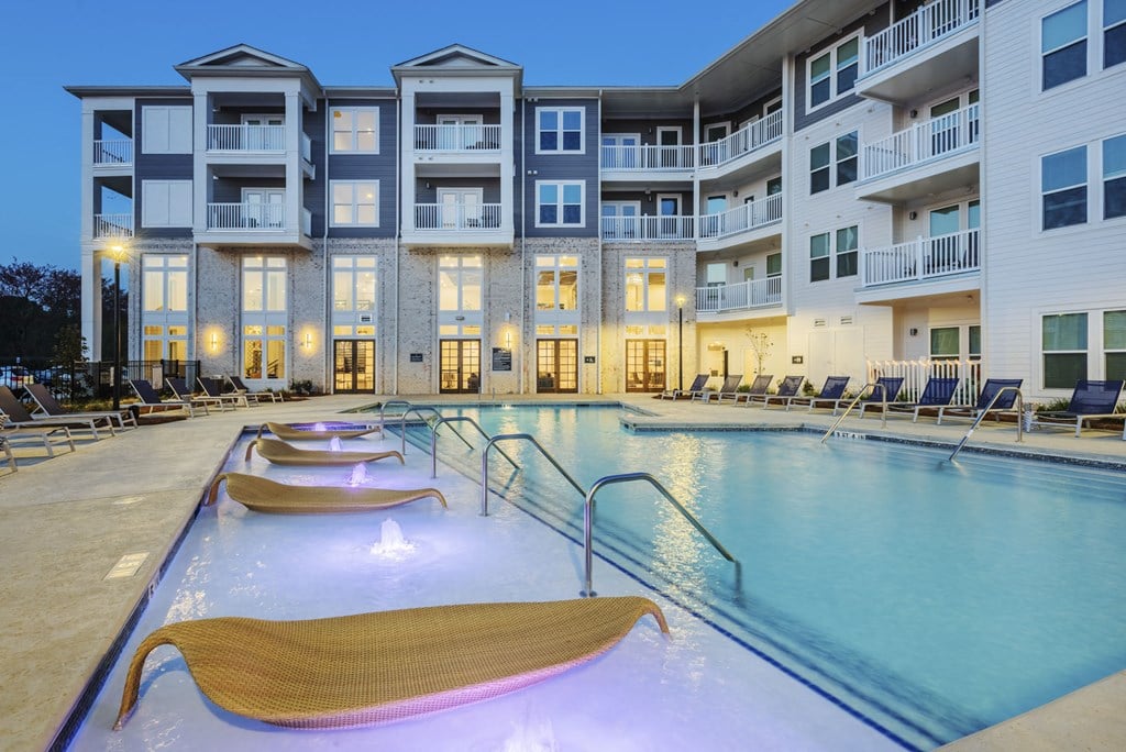 an apartment building with a swimming pool and lounge chairs