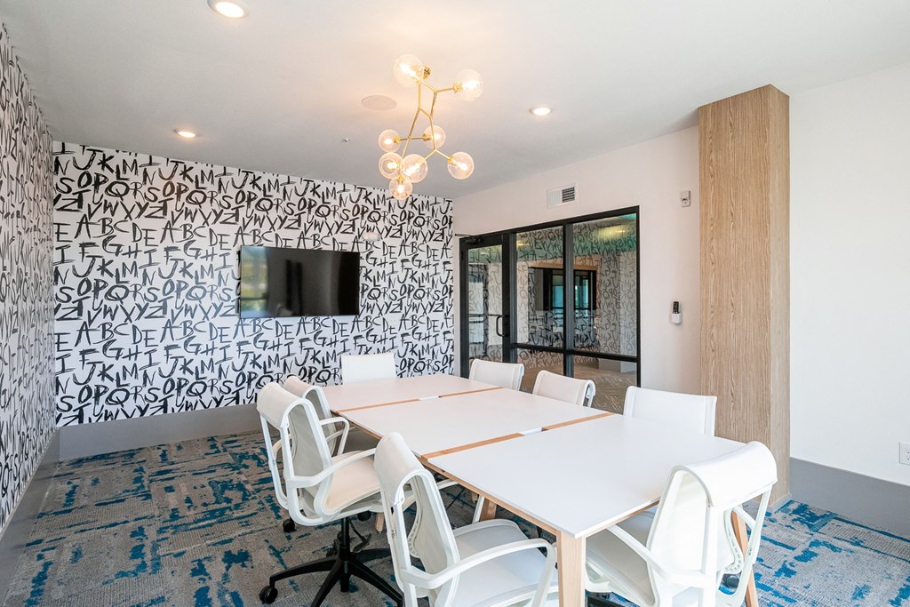 a conference room with white tables and chairs and a tv on the wall