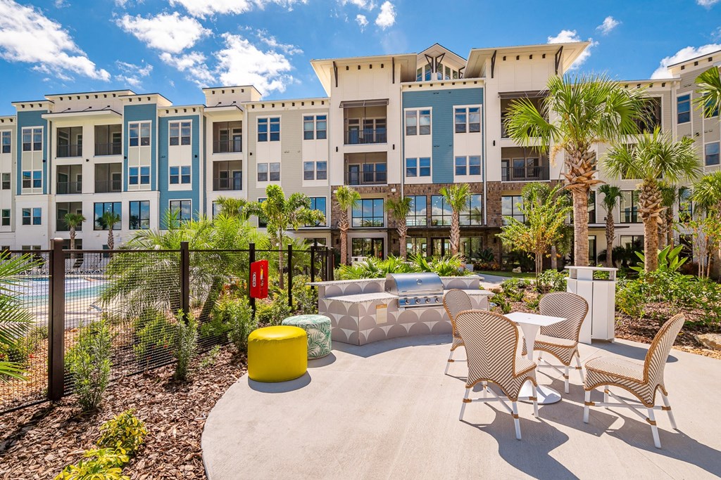 an outdoor patio with chairs and tables in front of an apartment building