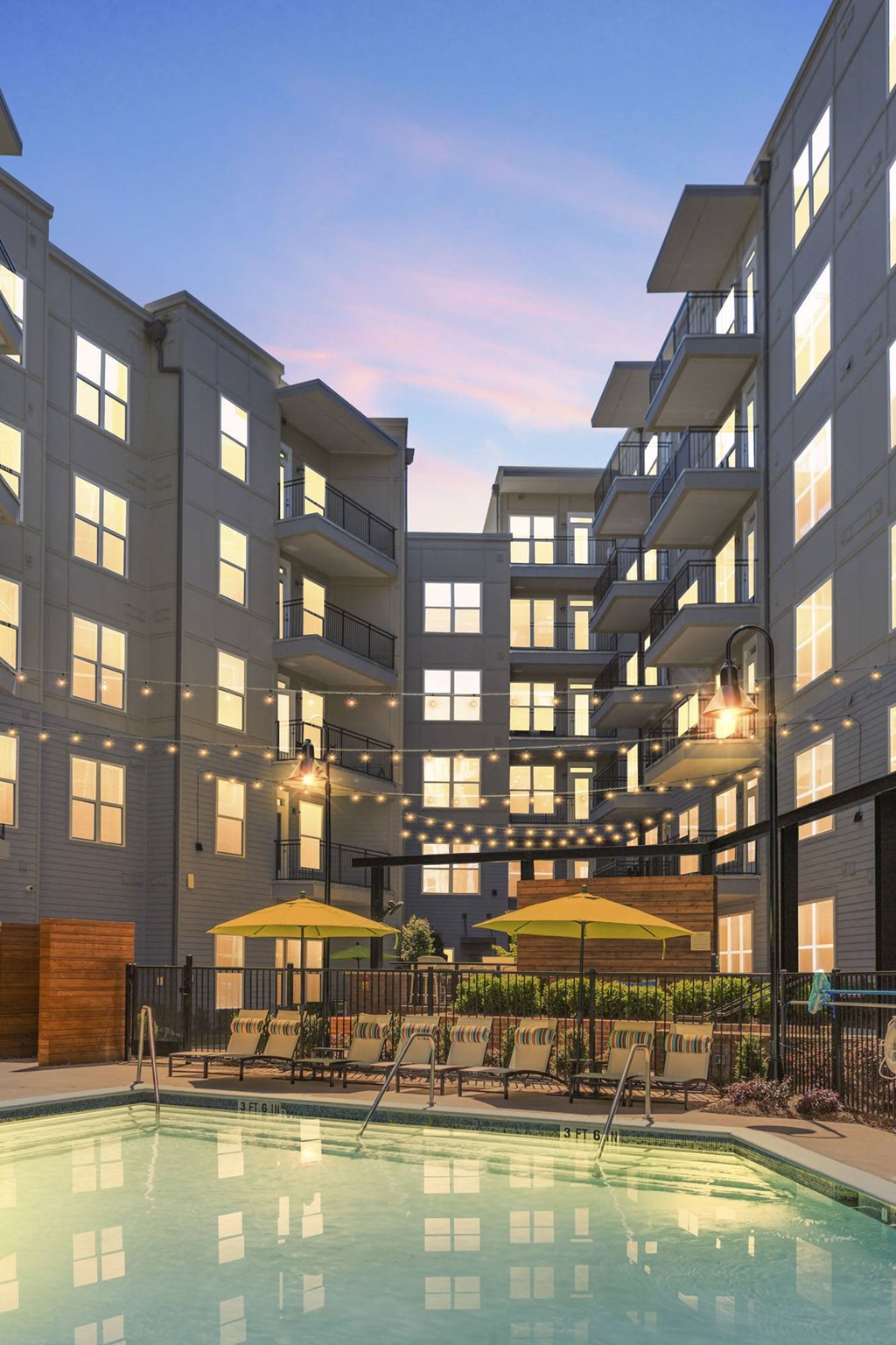 a swimming pool in front of a building with pool chairs and umbrellas