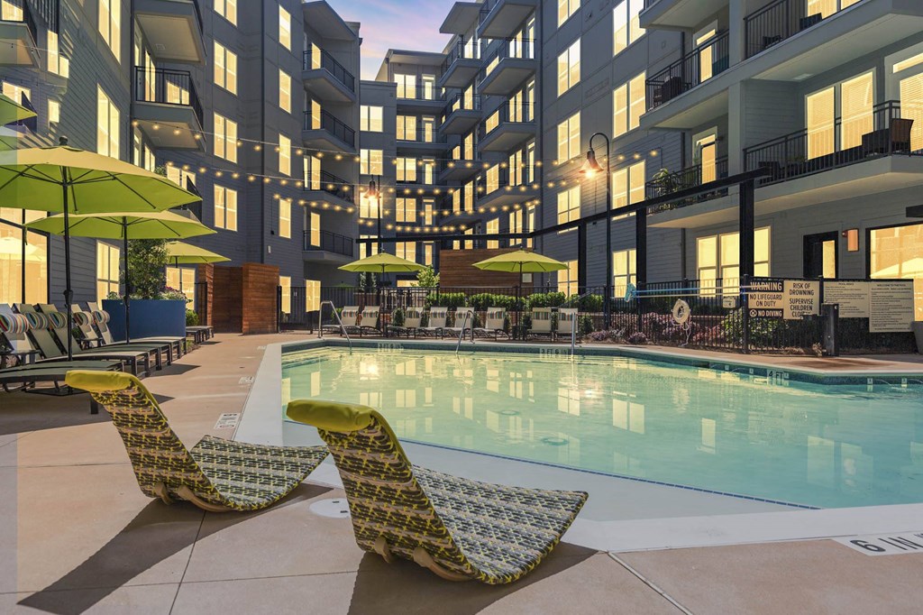 a swimming pool with chairs and umbrellas in front of a building