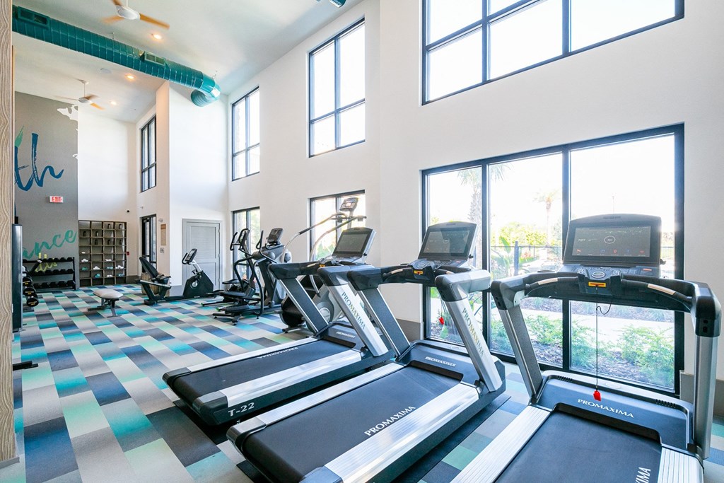 a gym with cardio equipment and windows in a building