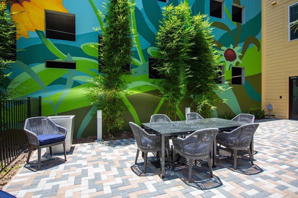a patio with a table and chairs in front of a colorful wall