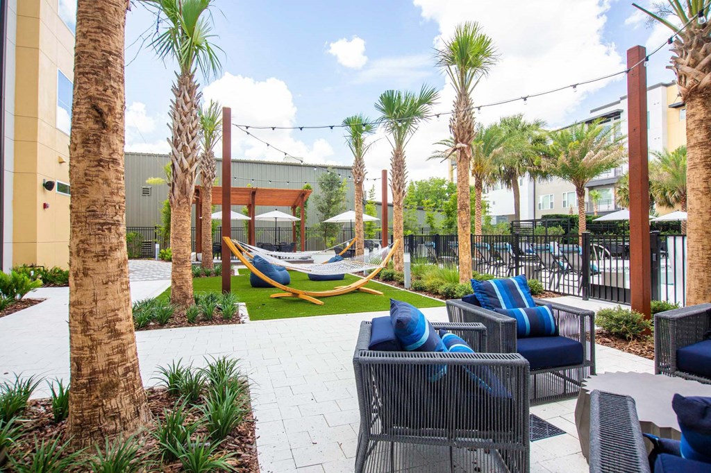 a patio with chairs and hammocks and palm trees