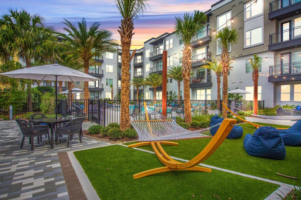 a courtyard with hammocks and tables and buildings with palm trees