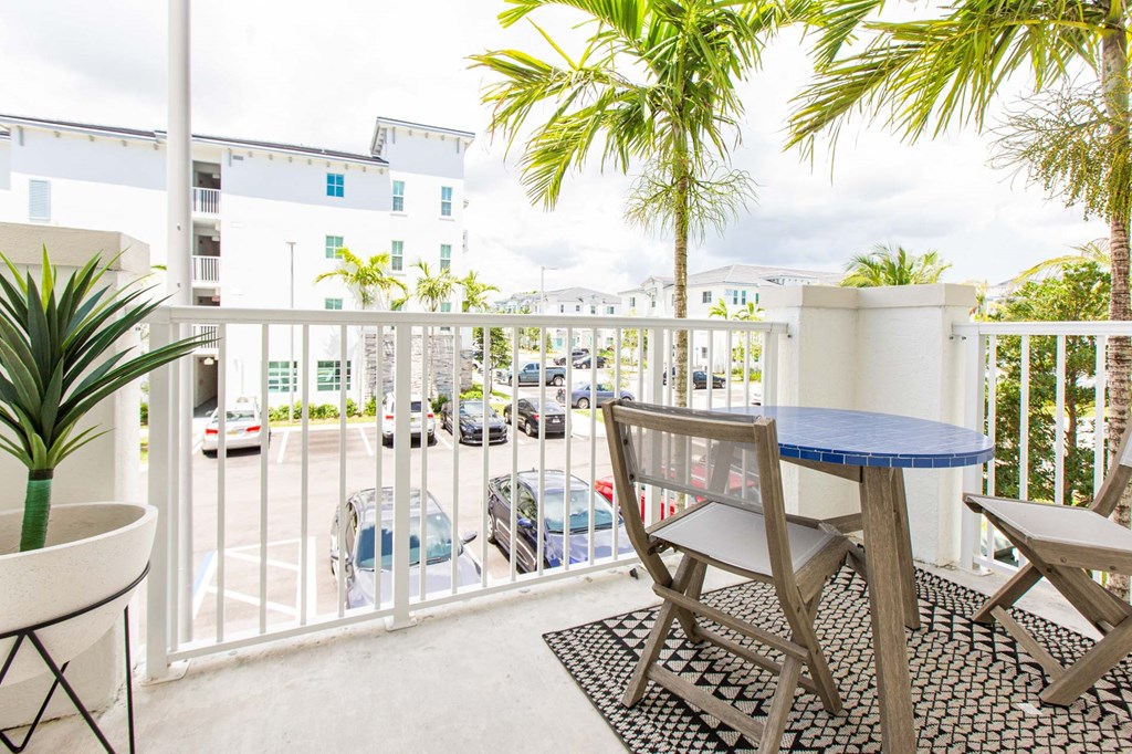 a balcony with a table and chairs and a view of a parking lot