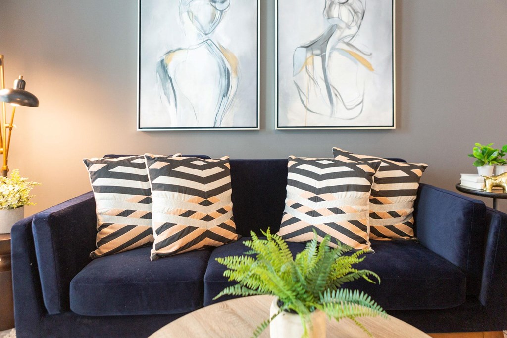 a blue couch with pillows and two paintings on the wall