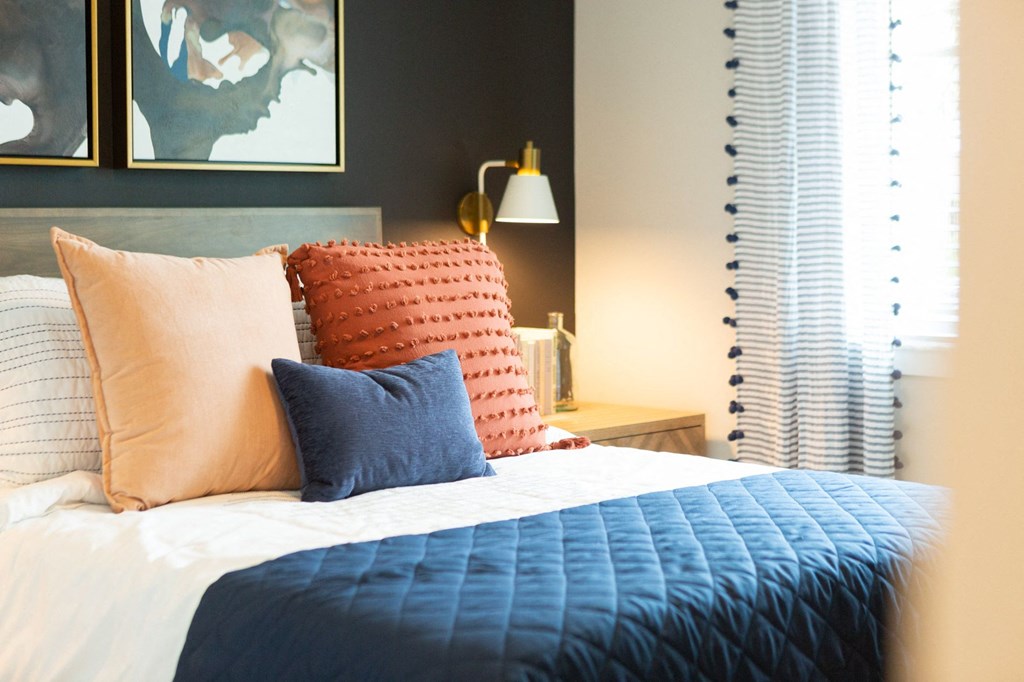 a bed with orange and blue pillows and a blue blanket
