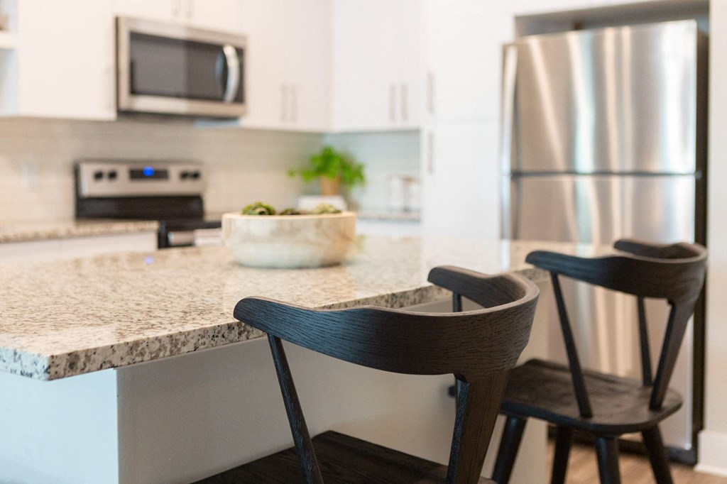 a kitchen with a marble counter top and two wooden chairs