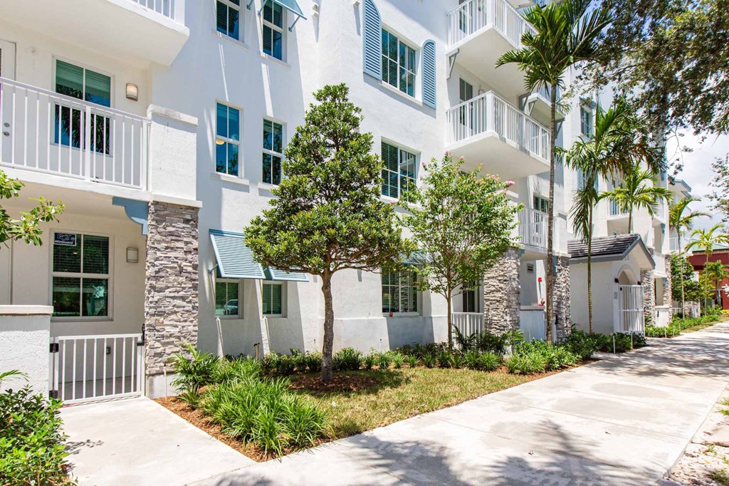 an exterior view of an apartment building with a sidewalk and trees