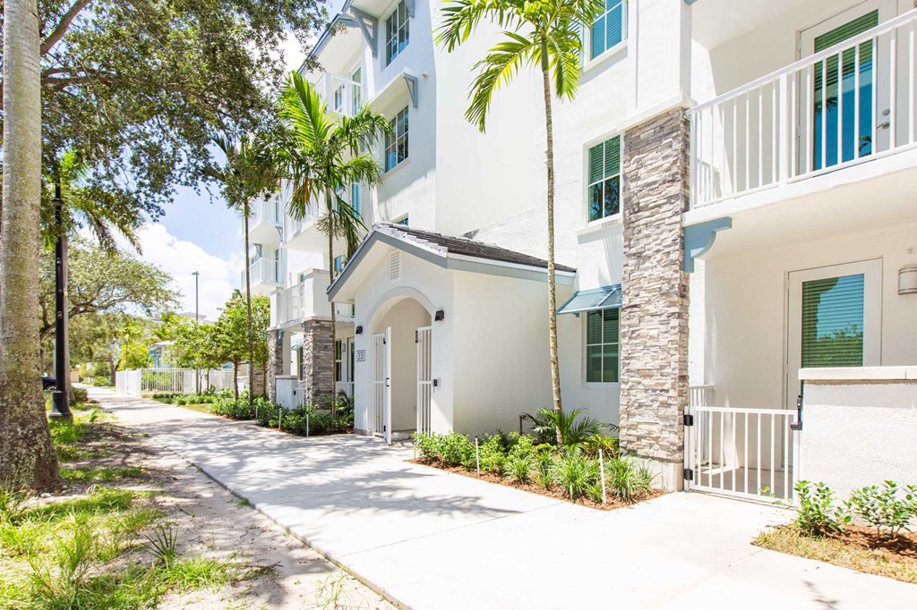 a white apartment building with a sidewalk and palm trees