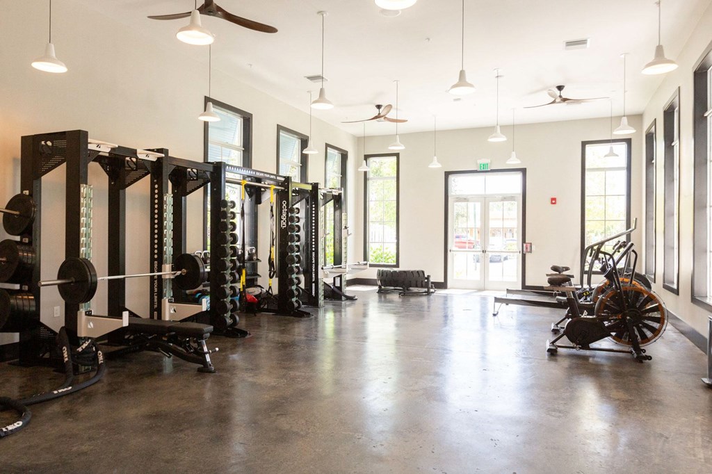 a gym with weights and other equipment in a building with windows