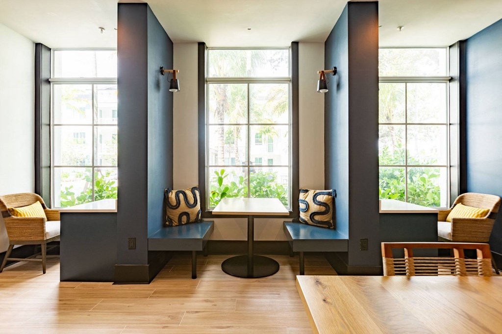 a living room with tables and chairs and large windows