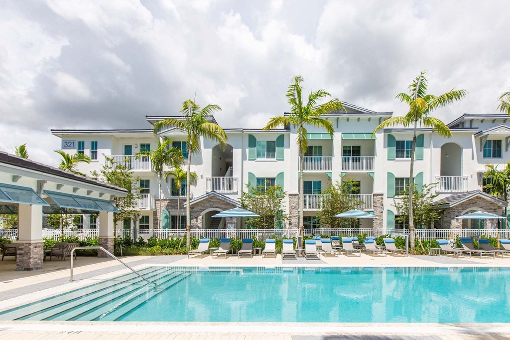 a large swimming pool in front of a hotel with palm trees
