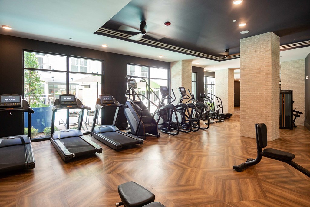 a gym with cardio equipment and large windows