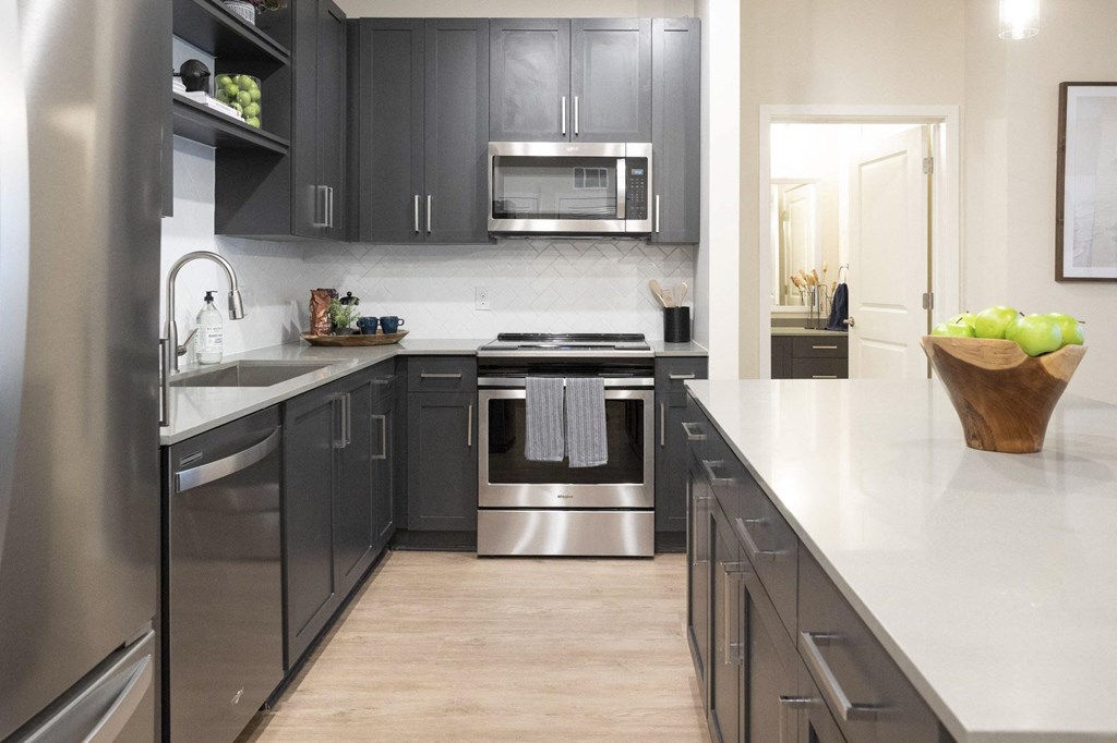 a modern kitchen with stainless steel appliances and white countertops