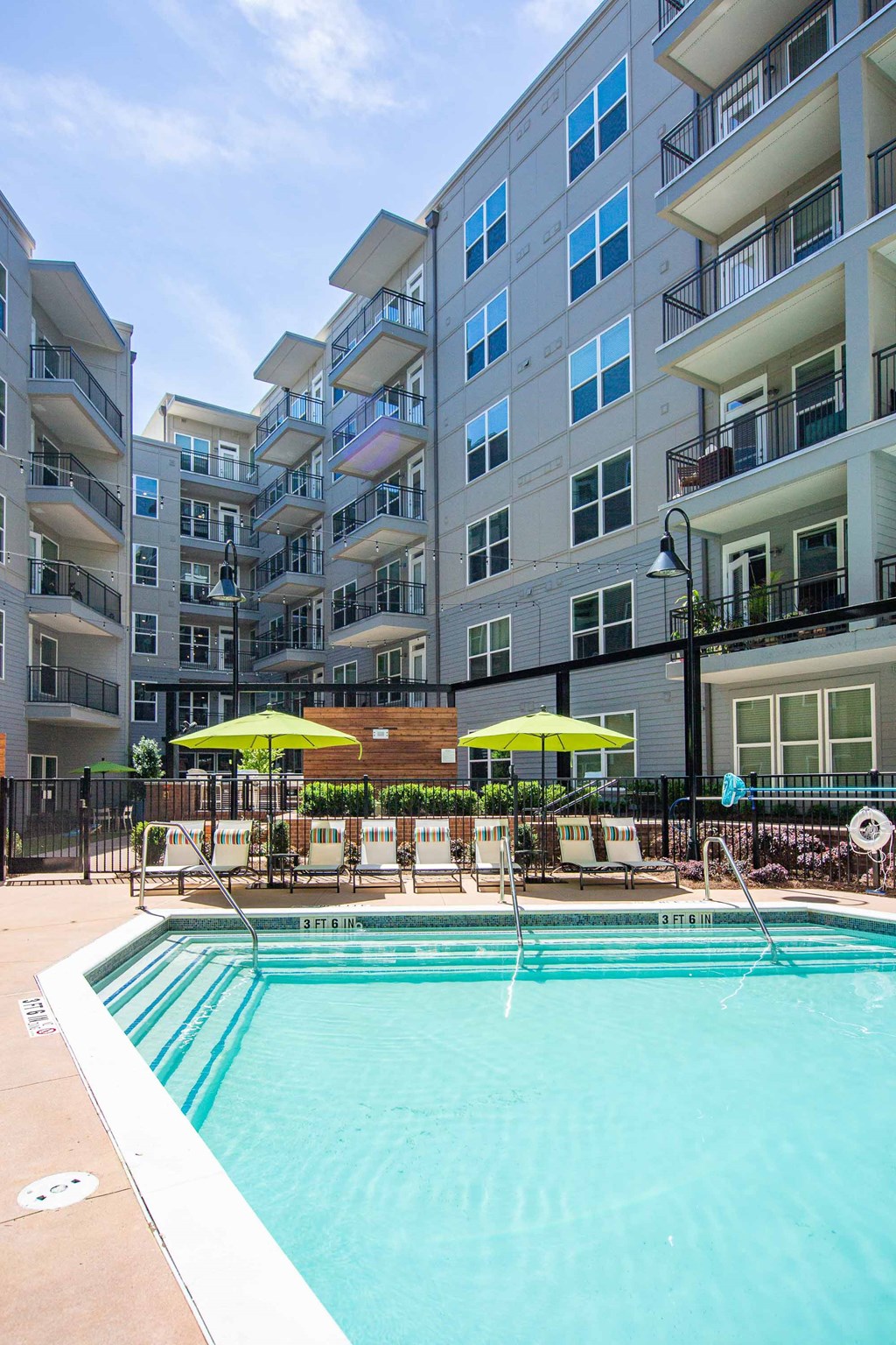 Pet-Friendly Apartments in Atlanta, GA - Live 8 West - Pool Area with Lounge Chairs, Green Umbrellas, and View of Balconies and Building Exterior