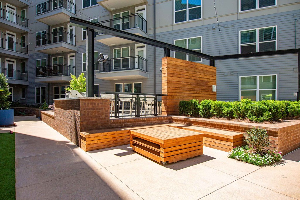 a patio with a wooden bench in front of an apartment building