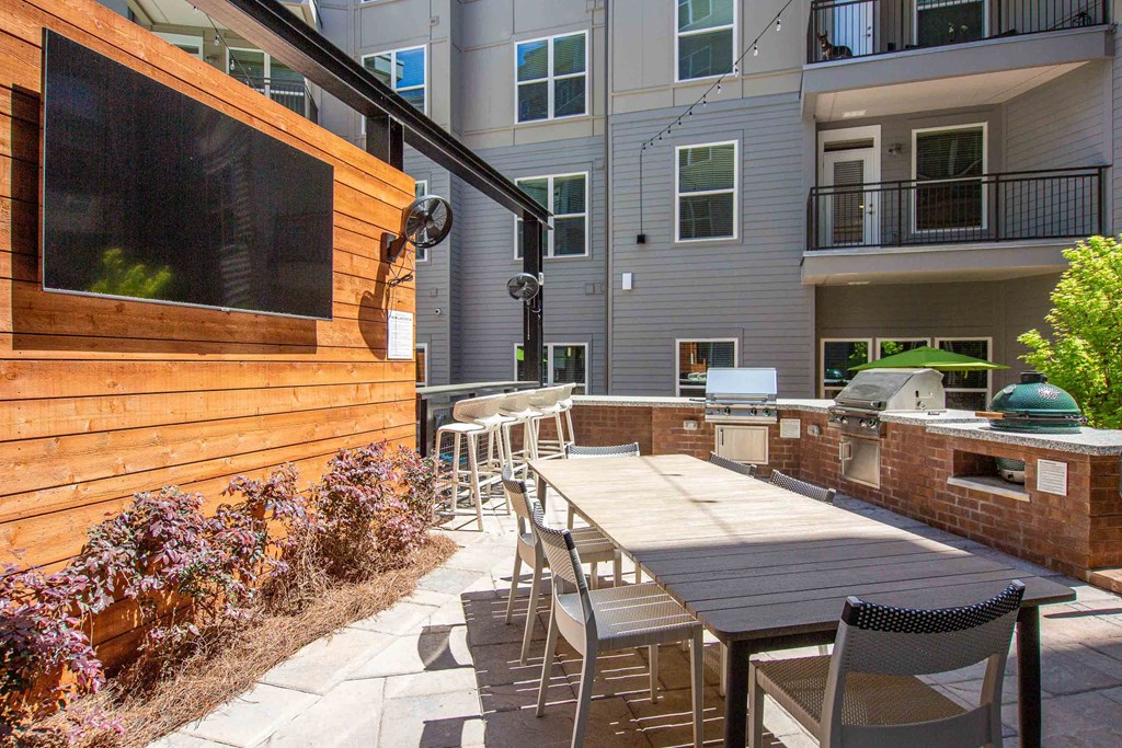 a patio with a wooden table and chairs and a grill