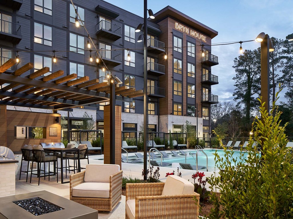 a patio with chairs and a pool in front of a building
