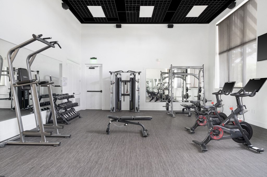a gym with various exercise equipment in a room with a window
