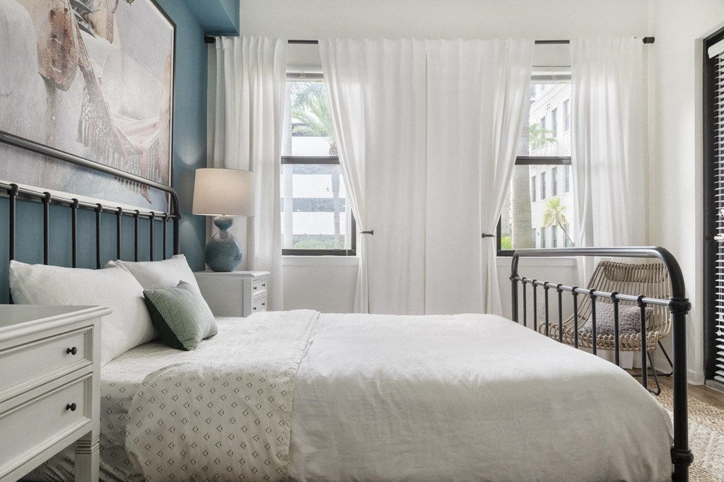 a bedroom with a bed and a window with white curtains