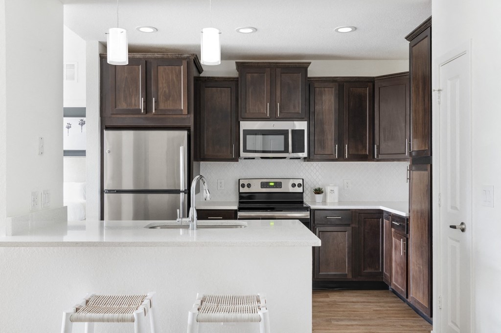 a white kitchen with dark wood cabinets and stainless steel appliances
