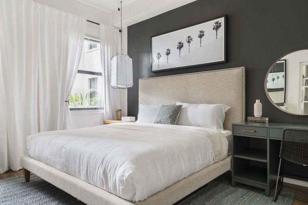 a bedroom with a white bed and a black wall and white curtains