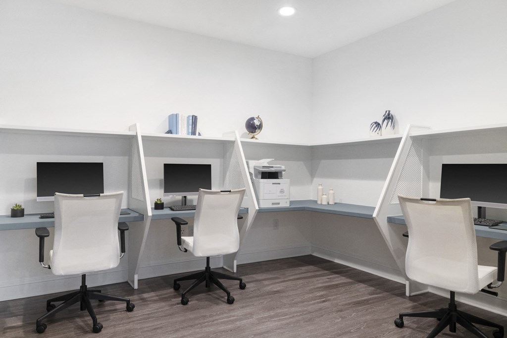an office with three desks and three chairs and two monitors