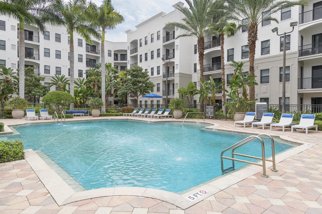 a swimming pool at an apartment complex with palm trees
