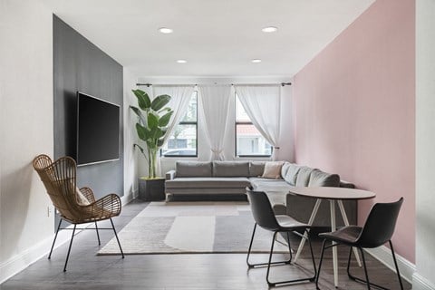 a living room with pink walls and a couch and a table and chairs