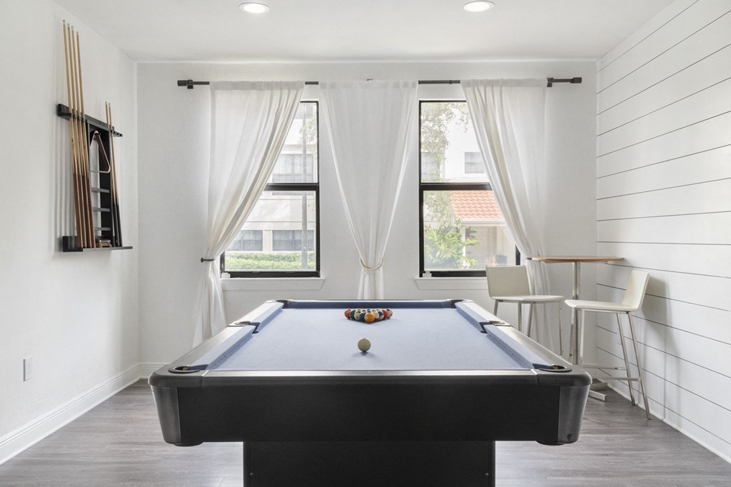 a pool table in a room with white walls and white curtains