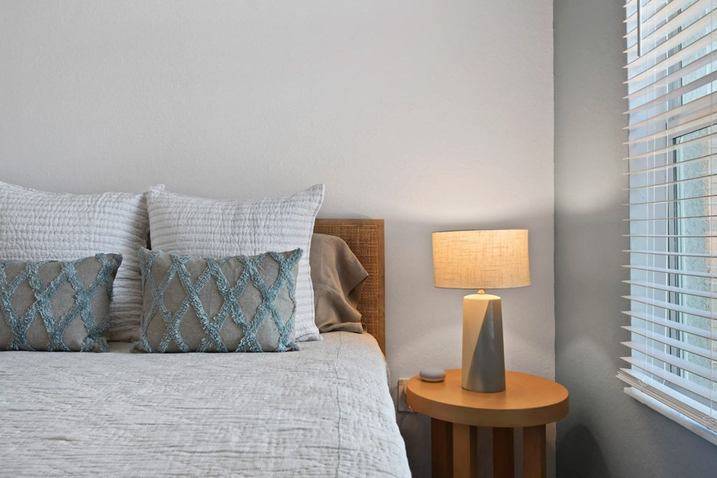 a bedroom with a bed with pillows and a table with a lamp