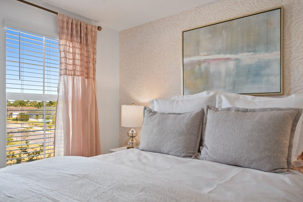 a bedroom with a bed with pillows and a window