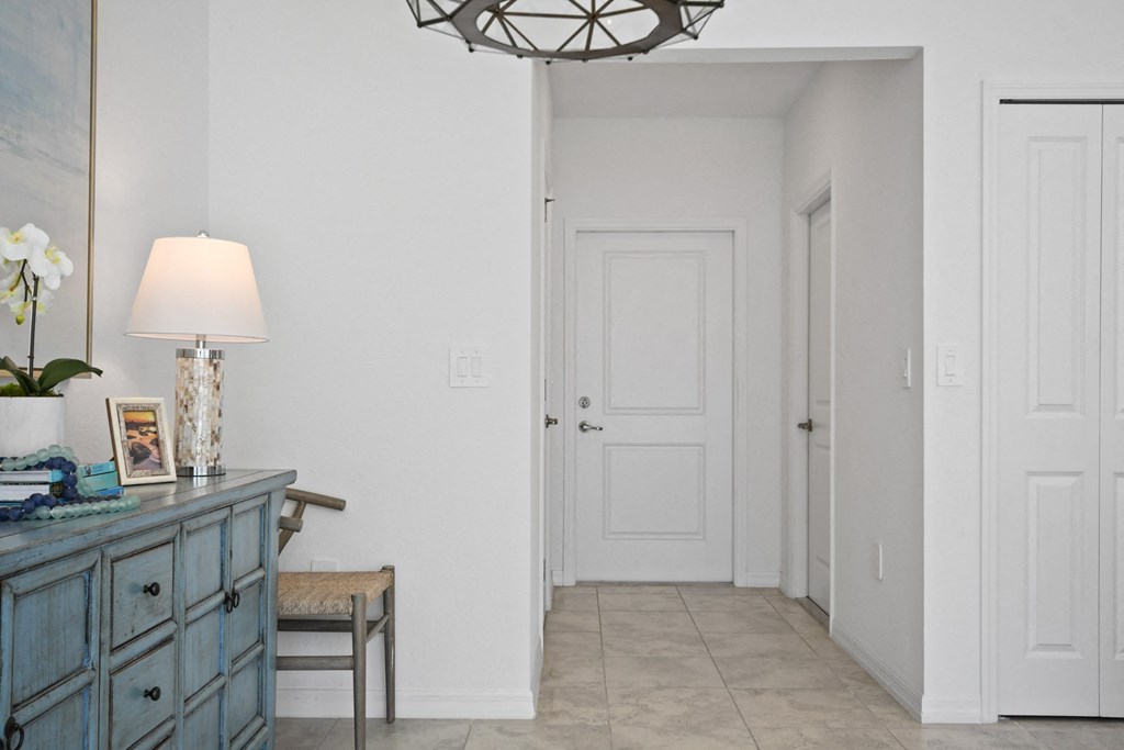 a hallway with white doors and a blue dresser with a lamp and a table