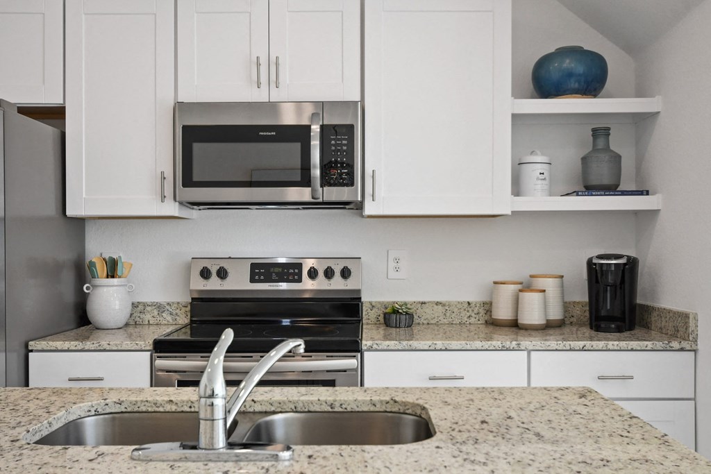 a kitchen with white cabinets and a sink and a microwave
