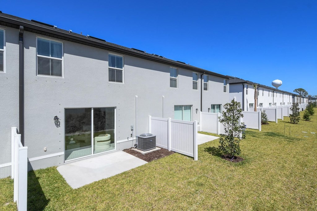 a row of white apartments with white fences and grass