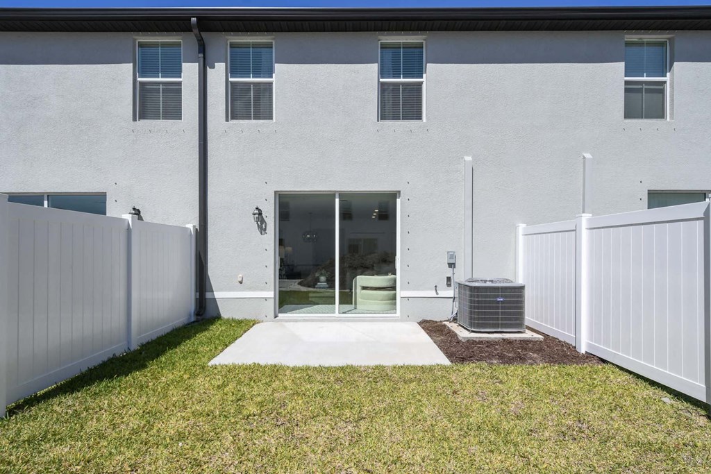 the front of a white building with a white fence and grass