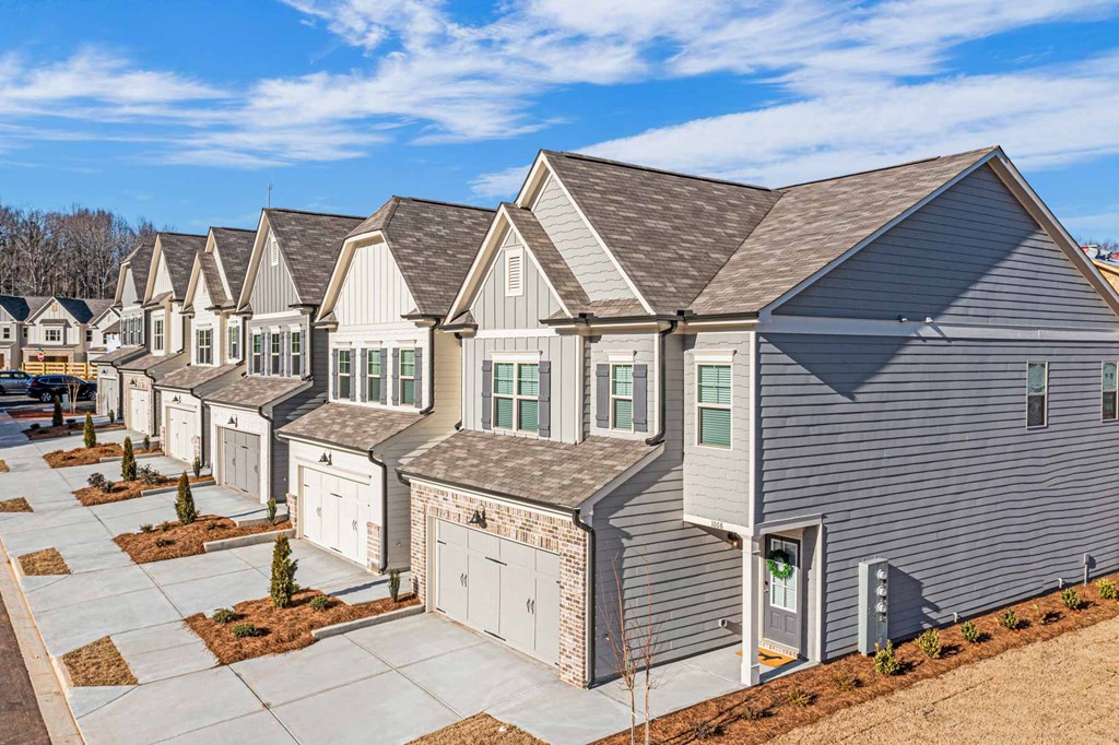 a row of gray houses with white doors and a sidewalk