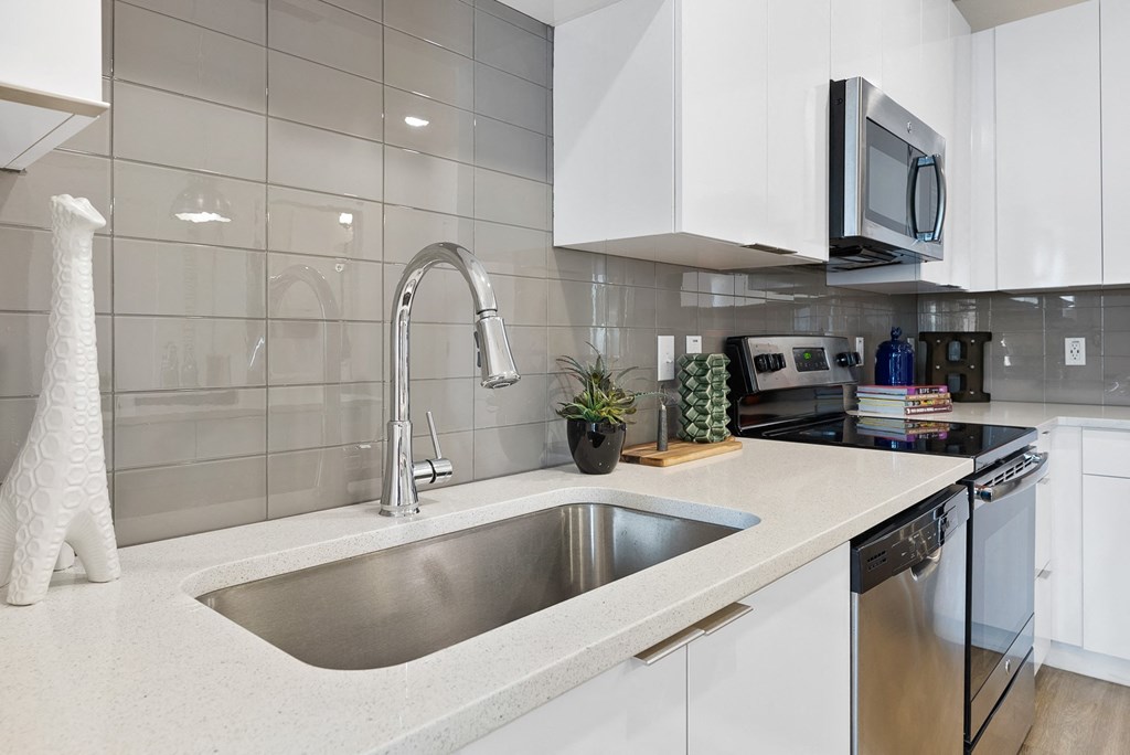 a kitchen with white cabinets and a stainless steel sink