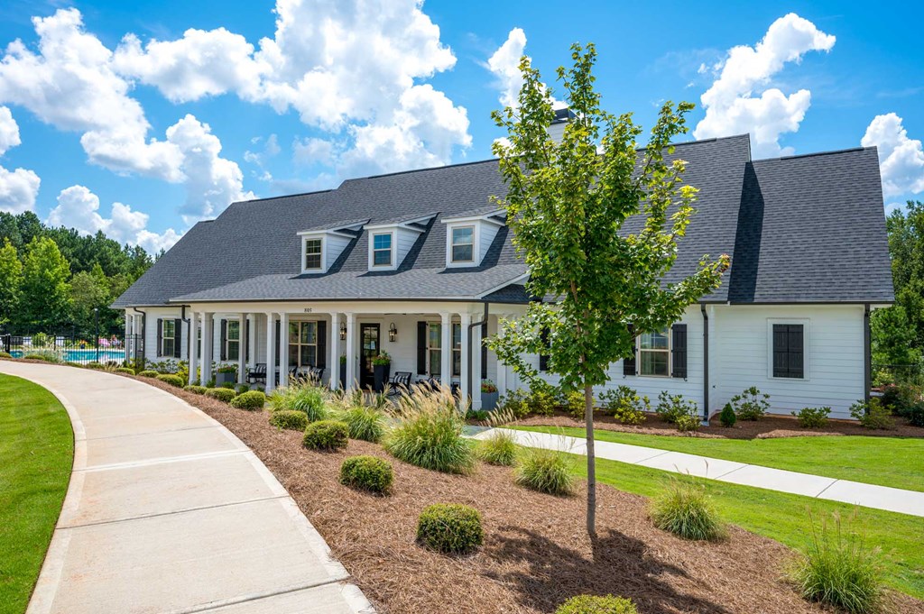 a white house with a sidewalk and a tree in front of it