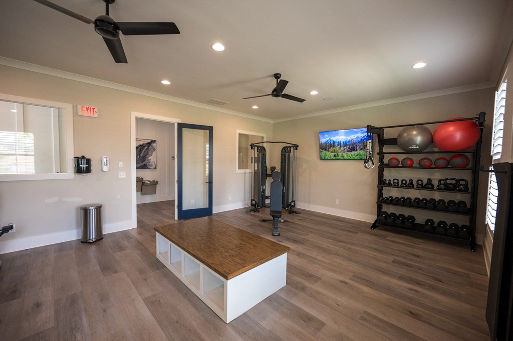 a home gym with a wooden floor and a table and a tv