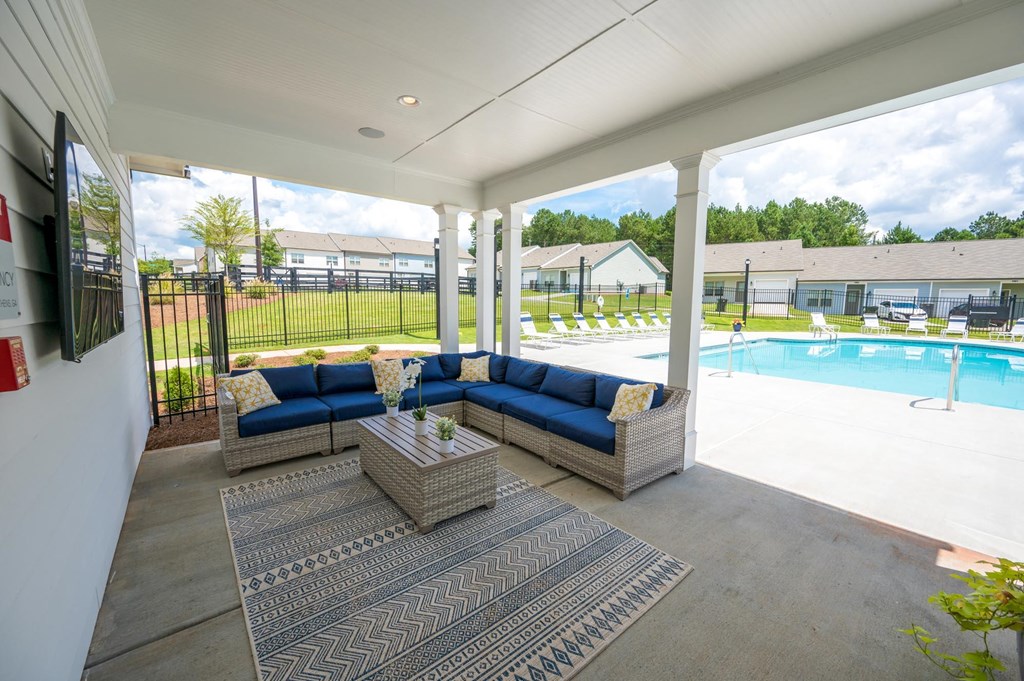 a covered patio with couches and a table next to a pool